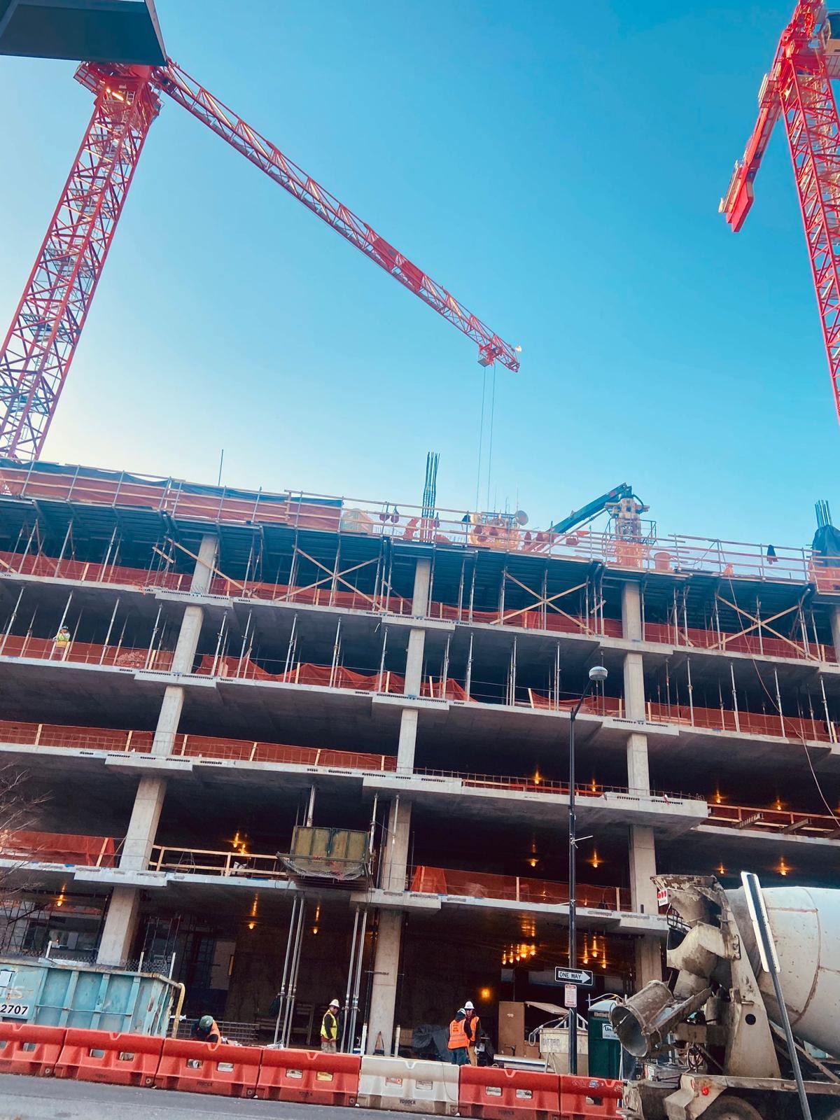Concrete building under construction with two tower cranes